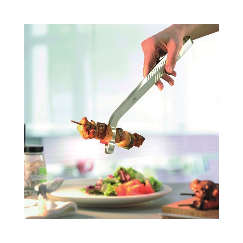 Μία μεταλλική λαβίδα ψησίματος με ένα σουβλάκι