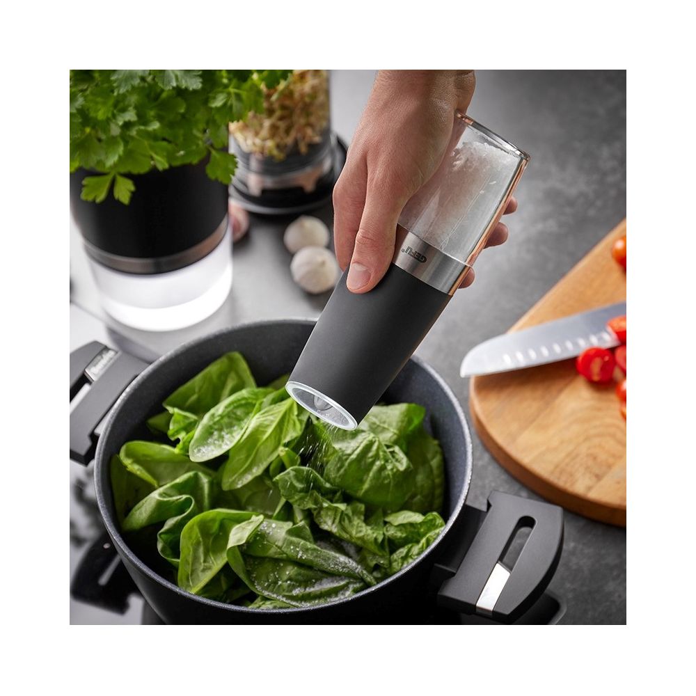 Μία κατσαρόλα με σπανάκι και από πάνω ένα χέρι που κρατάει έναν ηλεκτρικό μύλο μπαχαρικών με αλάτι