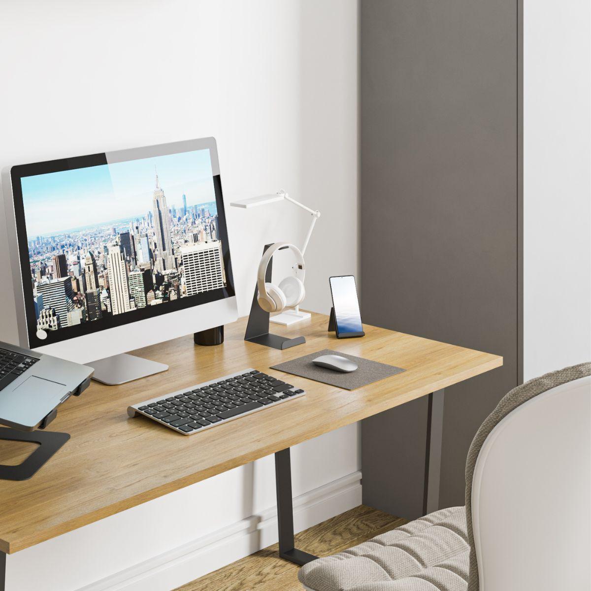 Ένα γραφείο εργασίας με μία οθόνη υπολογιστή, μία βάση για κινητό, ένα πληκτρολόγιο και μία μεταλλική βάση ακουστικών